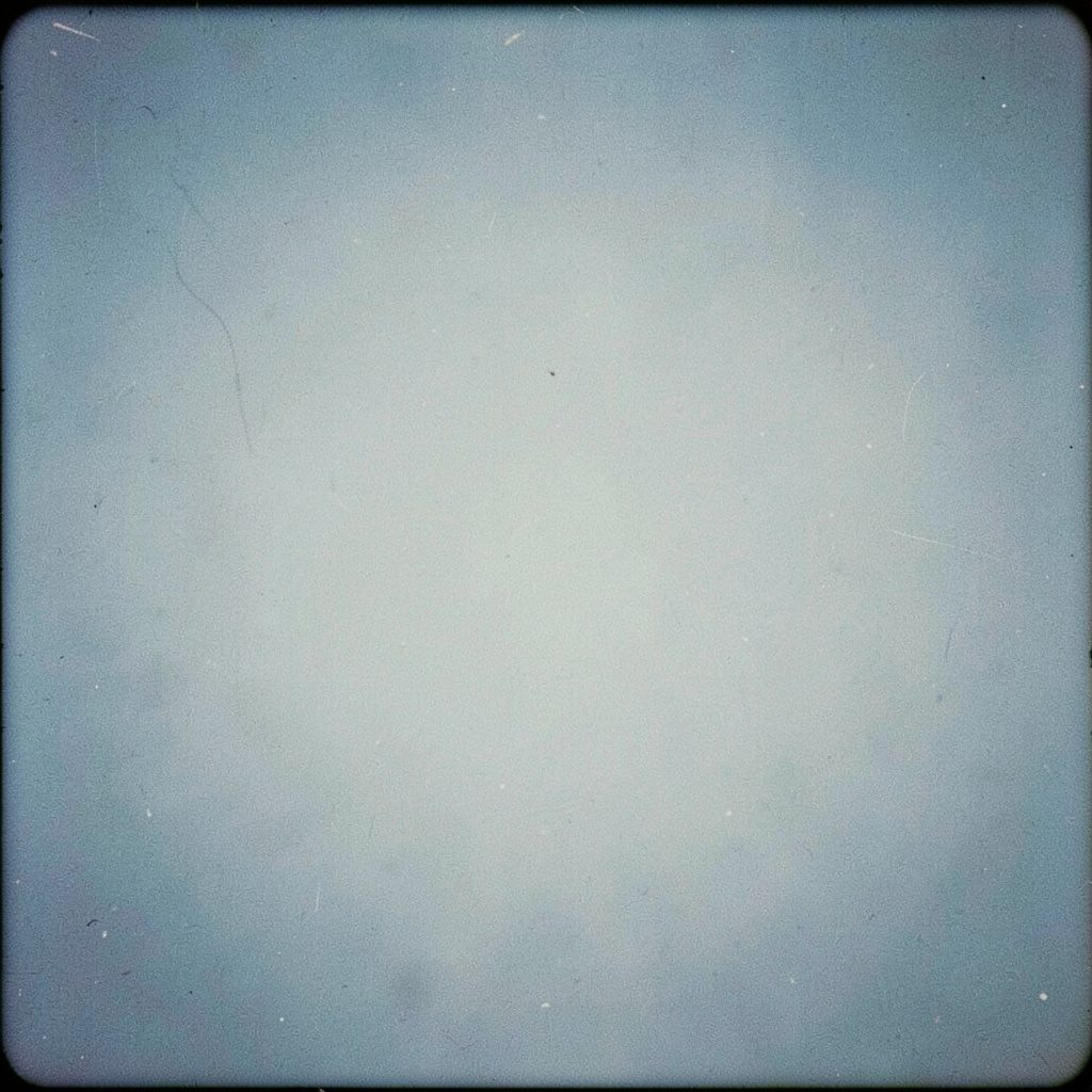 Dramatische Rennszene mit Fahrerfeld auf nasser Straße, kühle Blau- und Grautöne, analoge Filmfotografie mit sichtbarem Korn