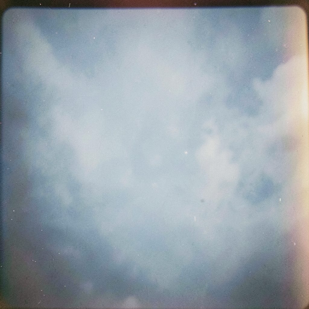 Nahaufnahme eines Rennrad-Lenkrads auf einer Landstraße, weiches Morgenlicht, cremefarbene und tiefblaue Töne, analoge Filmfotografie mit sichtbarem Korn